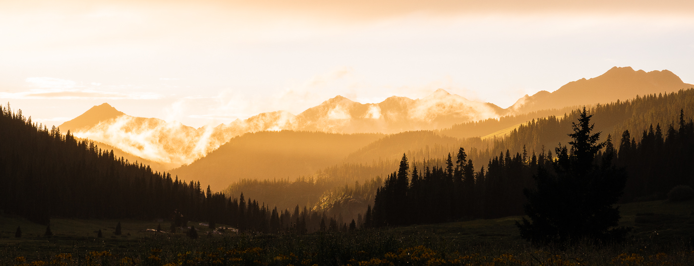 Panoramic view of a golden colored mountain chain at sunset