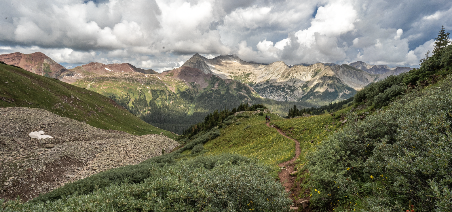 Looking down trail towards fourteener Capital Peak and a wide open cloudy moody vista